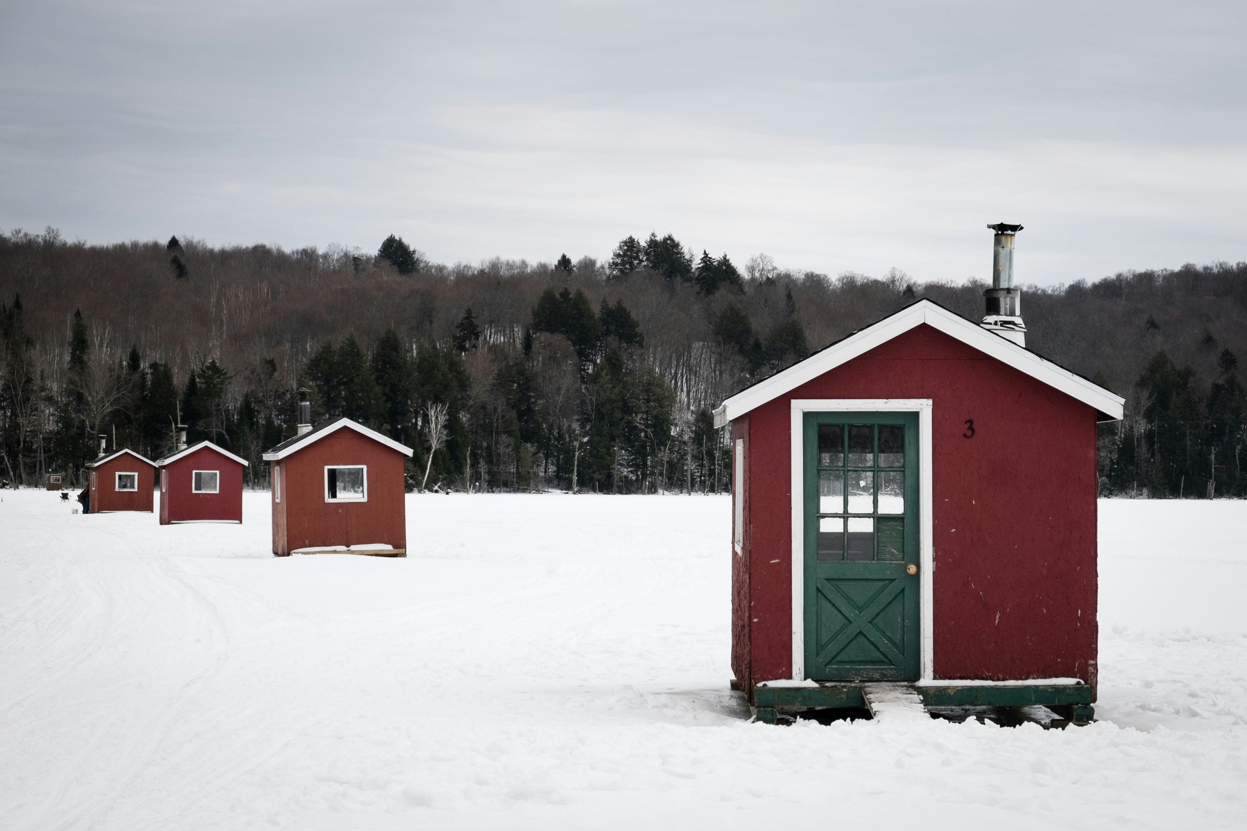 Red ice fishing huts lined up on a snowy Midwest lake